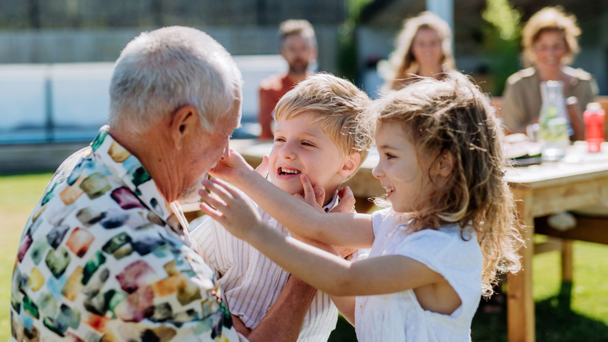 A grandfather playing with his grandchildren outdoors