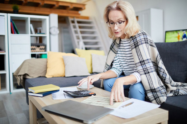 A middle-aged woman using a calculator and looking at financial paperwork