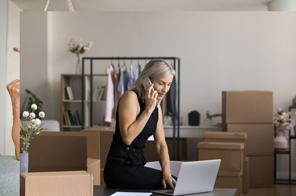 Female boss taking notes on a laptop as she discusses with someone on the phone